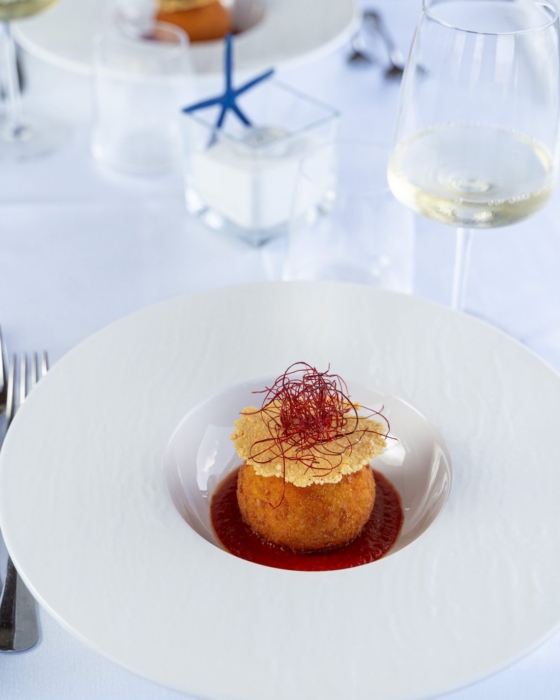 Arancina impiattata con cialda e fili di peperoncino
