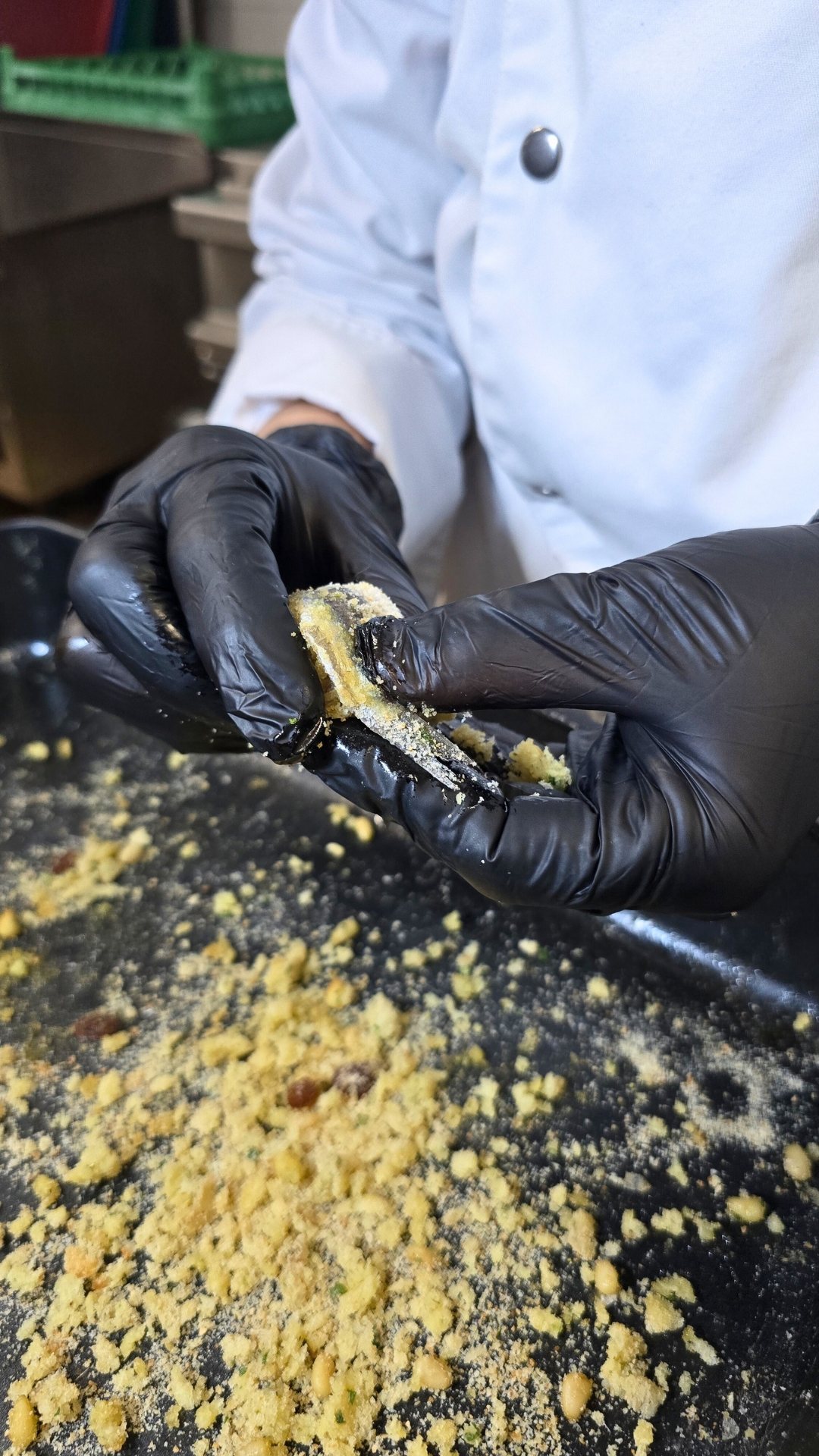 Le mani della chef mentre preparano il pesce con la mollica